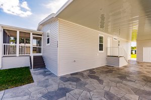 Angled view of a house with a screen room, stairs, carport and shed