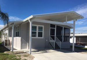 Angled view of a house with a screen room, stairs and a small carport