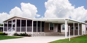 Angled view of a house with a large screen room, carport, stairs and a small shed