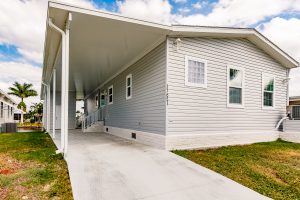 Side view of a house with a carport, stairs and a shed