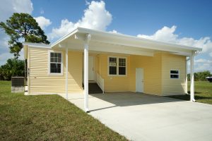 Front view of a house with a small carport, stairs and a small shed
